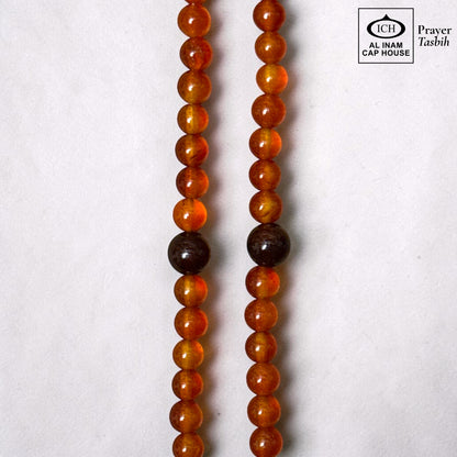 AL INAM CAP HOUSE amber and brown crystal prayer beads with smooth, glossy finish. Features uniform sizing and natural color variations.