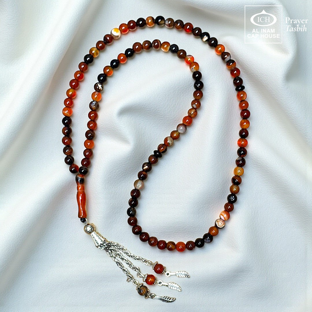 AL INAM CAP HOUSE Belgium Crystal Tasbih with amber, brown, orange, and black beads. Features a silver tassel and a smooth, polished finish.