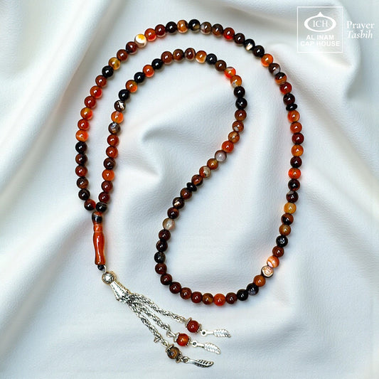 AL INAM CAP HOUSE Belgium Crystal Tasbih with amber, brown, orange, and black beads. Features a silver tassel and a smooth, polished finish.
