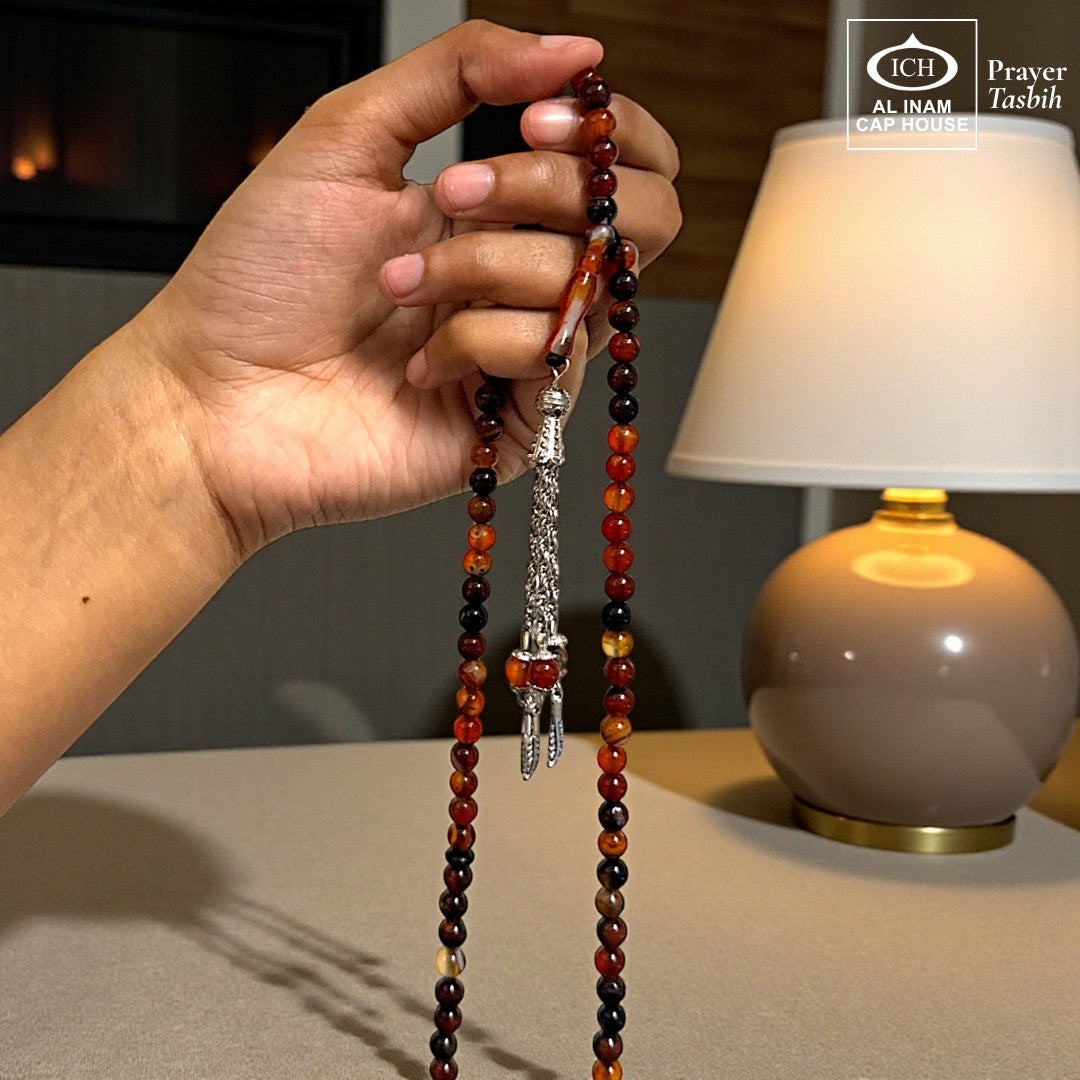 AL INAM CAP HOUSE Belgium Crystal Tasbih with amber, brown, orange, and black beads. Features a silver tassel.