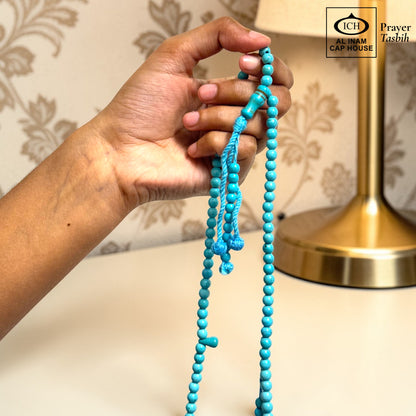 AL INAM CAP HOUSE blue Firoza (Turquoise) prayer beads with a blue tassel, held in a hand.